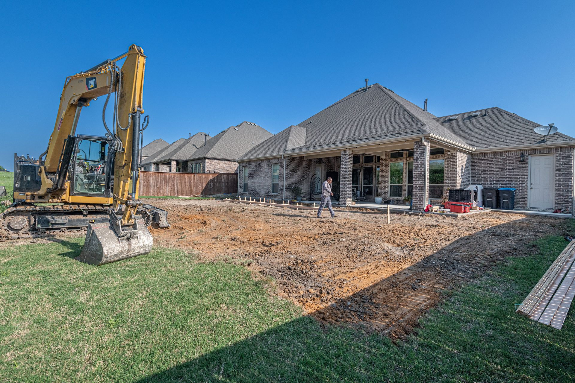 Excavator preparing a backyard site for a new concrete patio near Spartanburg, SC